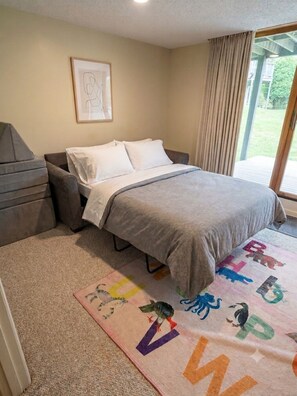 A bedroom with a bed, a sofa, a window with curtains, and a carpet with alphabet and animal designs. - Family friendly condo at Smugglers Notch Resort (Cambridge)