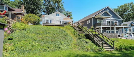 A residential area with houses, a grassy hill, and a wooden staircase leading to a porch.