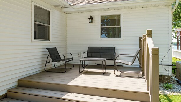 A covered porch with a table and two chairs, a window, and a lantern. - Paddle & Play on Long Lake - Lakefront Retreat (Scotts)