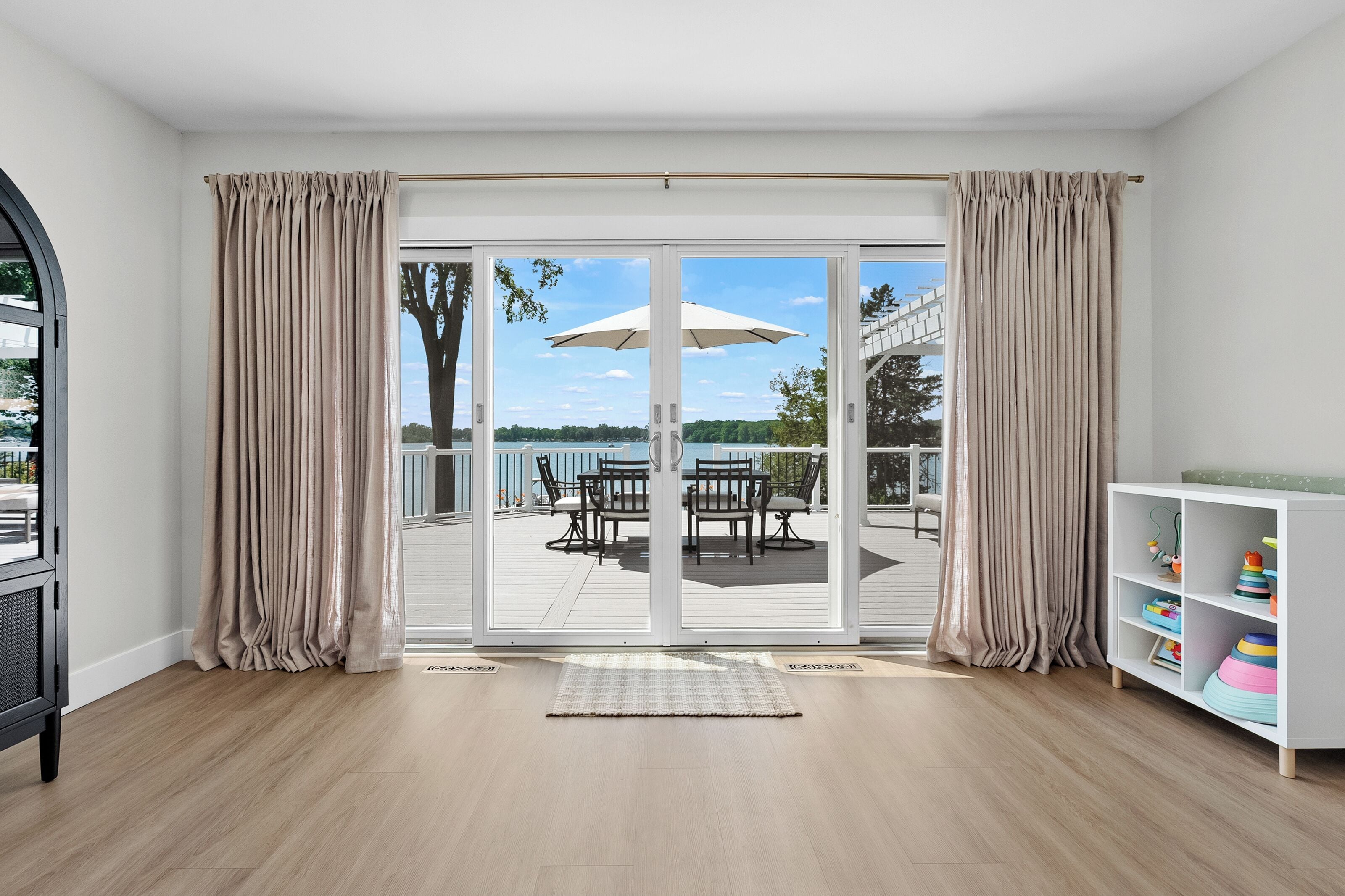 A room with a sliding glass door leading to an outdoor deck with a table and chairs.