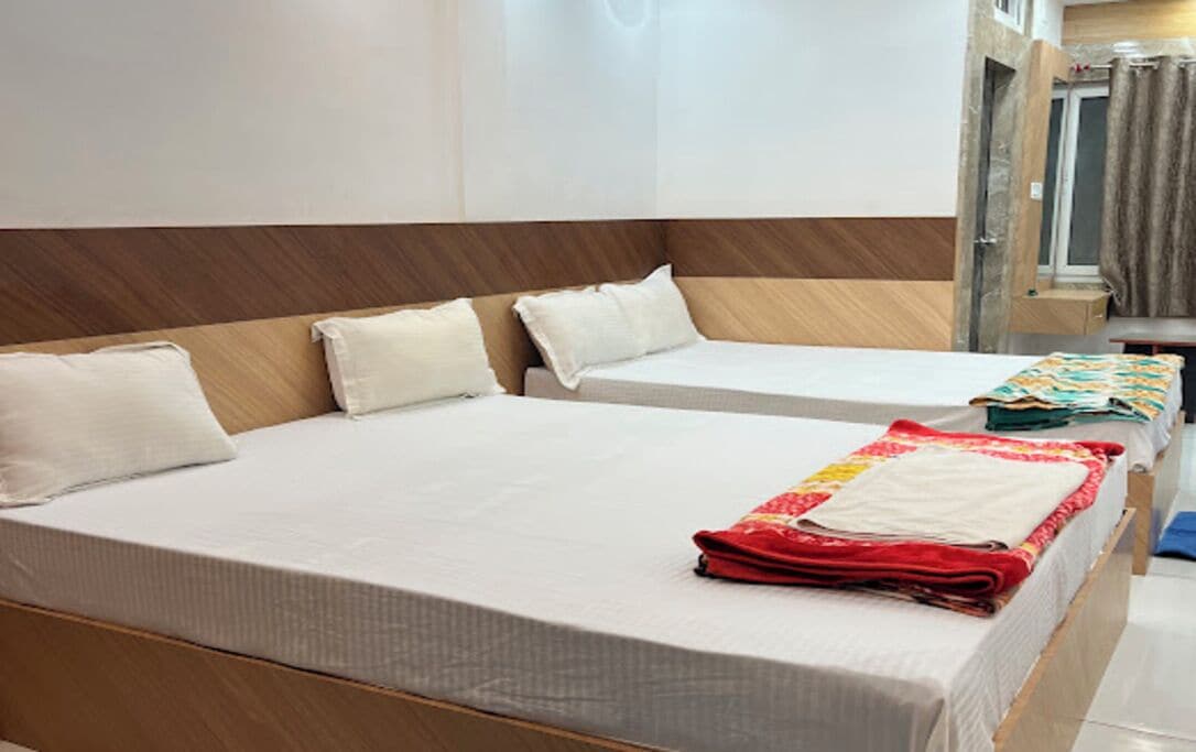 A hotel room with two beds, a wooden headboard, a bathroom with a shower, and a mirror.