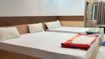 A hotel room with two beds, a wooden headboard, a bathroom with a shower, and a mirror.
