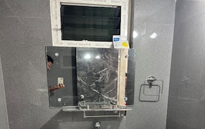 A bathroom with a mirror, a towel rack, and a window.