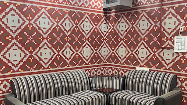 A room with a patterned wall, a ceiling fan, and a striped sofa.