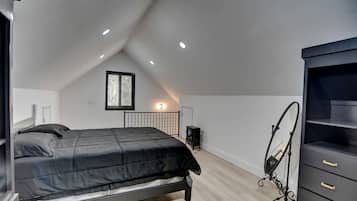 A bedroom with a bed, a dresser, a radiator, and a window.