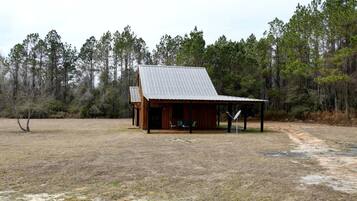 A rustic cabin with a metal roof, a porch, and a covered outdoor seating area.
