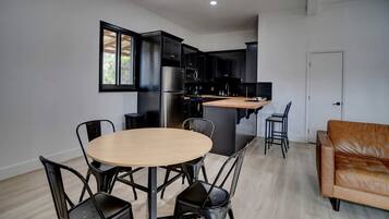 Una cocina moderna con gabinetes negros, un refrigerador de acero inoxidable y una isla de madera.