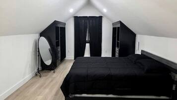 Ein Schlafzimmer mit einem Bett, einem Schminktisch mit Spiegel und einem Fenster mit Vorhängen.