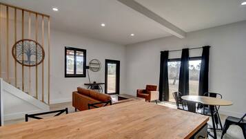A modern interior with a wooden dining table, a sofa, and a staircase.