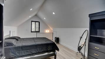A bedroom with a bed, a dresser, a radiator, and a window.