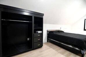 Ein Schlafzimmer mit Bett, Kleiderschrank und Regalelement.
