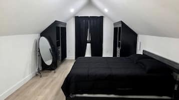 A bedroom with a bed, a vanity with a mirror, and a window with curtains.