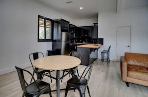 A modern kitchen with dark cabinetry, a stainless steel refrigerator, and a wooden island.
