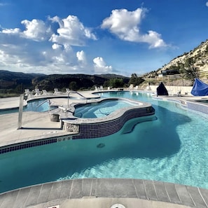 A swimming pool with a hot tub, lounge chairs, and a view of the mountains. - Fantastic Tiny House Fully Equipped with Glass Ceiling in Orderville, Utah (Orderville)