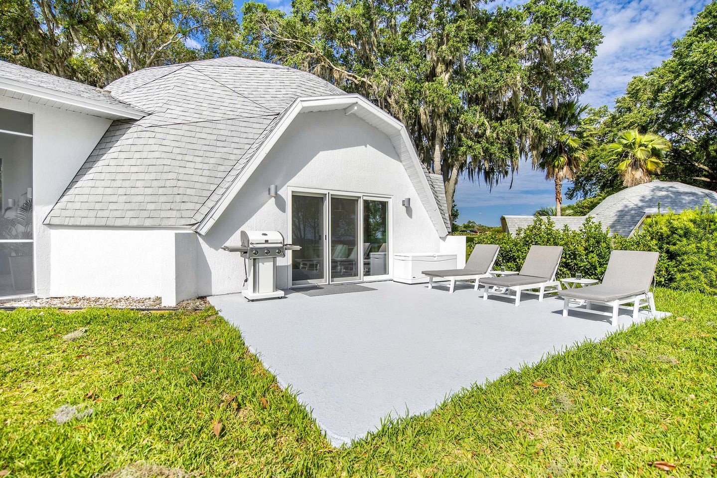Uma casa moderna com um alpendre, área de estar externa e vista para a água.