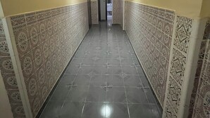 Un pasillo con paredes de diseño y suelo de baldosas, que conduce a una puerta al final.