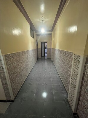 Un pasillo con paredes de diseño y suelo de baldosas, que conduce a una puerta al final.