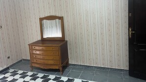 Una habitación con un aparador de madera, un espejo y una puerta negra.