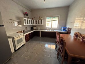 A kitchen with a dining table and chairs, a microwave, and cabinets.