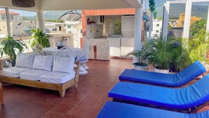 A covered outdoor area with a sofa, lounge chairs, and potted plants. - Close to the ocean—the perfect spot to explore Puerto Plata on foot (Puerto Plata)
