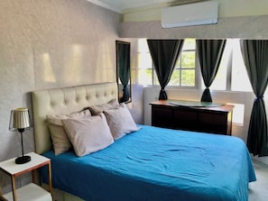 A bedroom with a bed, bedside table, lamp, and a desk with a chair. - Close to the ocean—the perfect spot to explore Puerto Plata on foot (Puerto Plata)