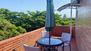 A balcony with a glass table, two chairs, and a green umbrella. - Close to the ocean—the perfect spot to explore Puerto Plata on foot (Puerto Plata)