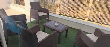 An outdoor seating area with wicker furniture and a small table, surrounded by a wooden fence.