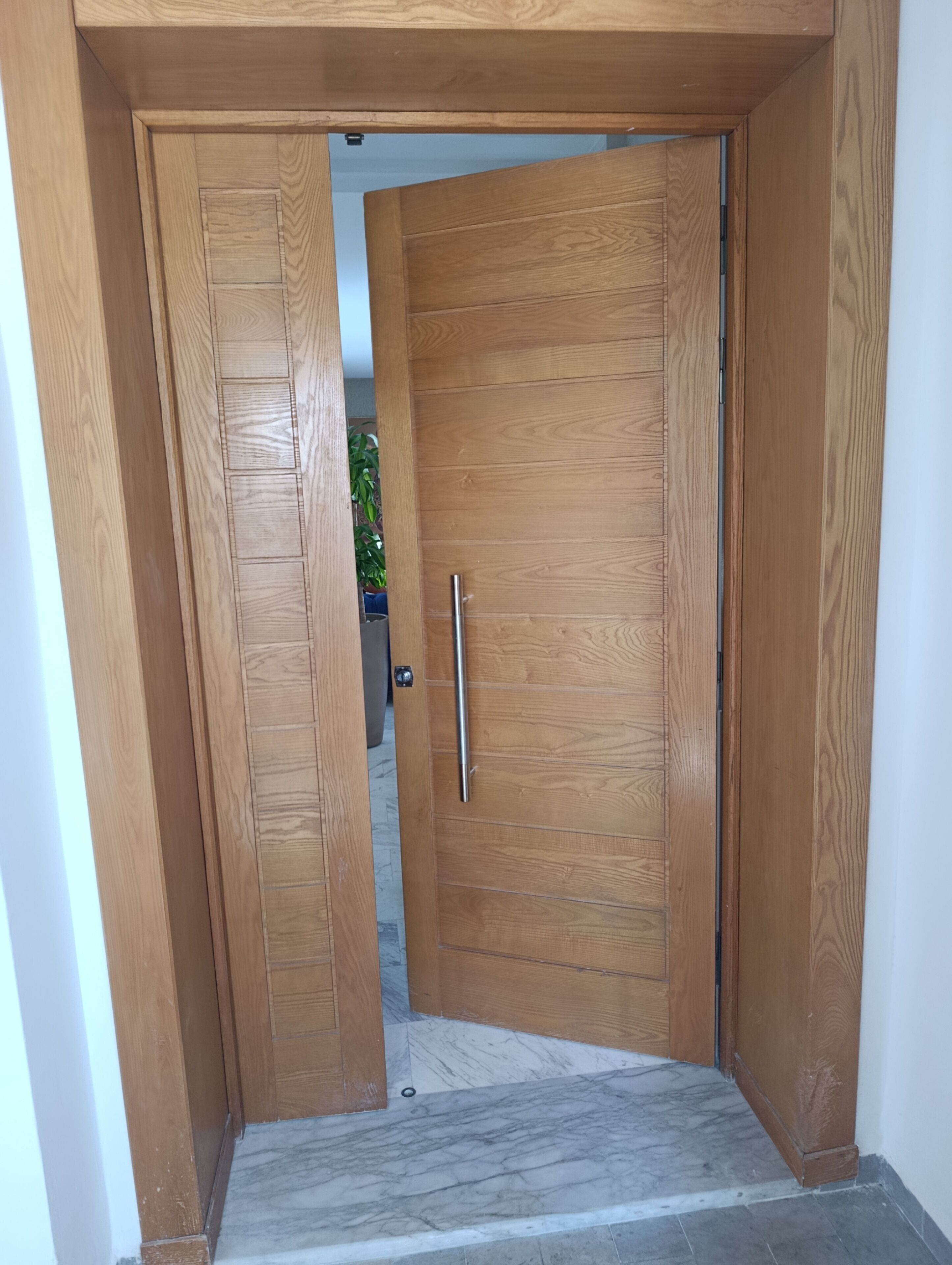 A wooden door with a handle, leading to a room with a tiled floor.