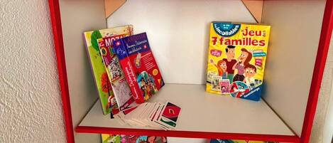 A shelf with children's books, a stuffed toy, and a cactus.