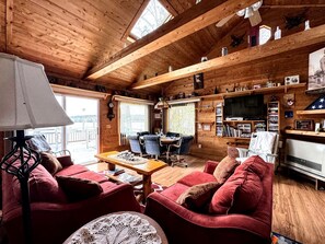 Un acogedor interior de cabaña con comedor, un conjunto de sofás y una televisión.