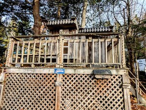 Une structure en bois avec une clôture à treillis, un panneau indicateur et une plateforme en bois.