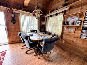 Interior de madera con una mesa de comedor, sillas y una lámpara colgante.