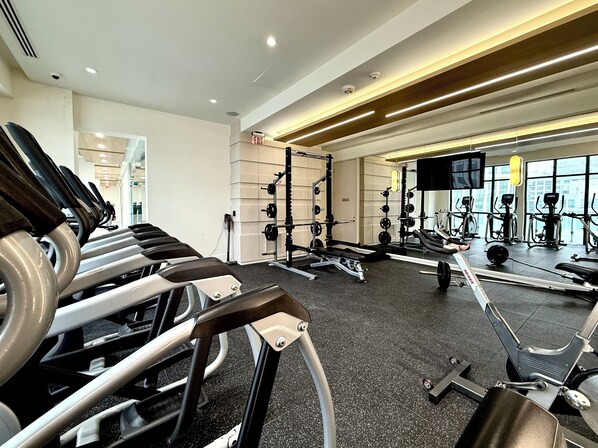A gym with treadmills, weight machines, and a mirrored wall.