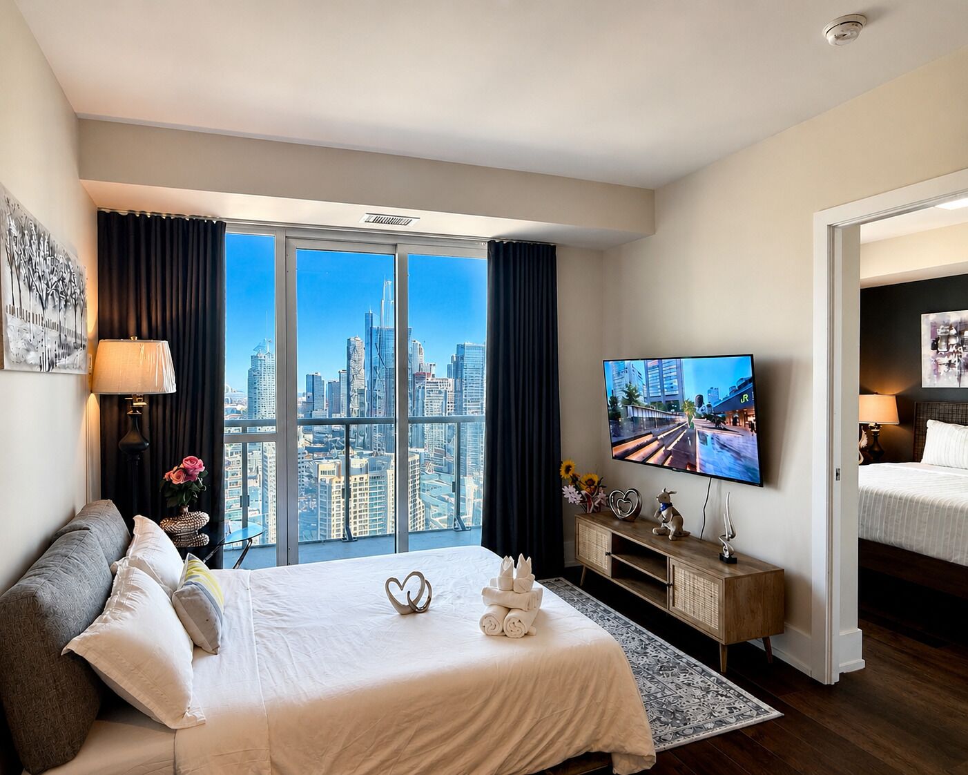 A hotel room with a bed, a television, a city view, and a balcony.