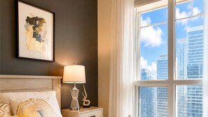 A hotel room with a large bed, a nightstand with a lamp, a framed picture on the wall, and a window with a city view. - Chic RogersCenter MTCC 2B2B Lake&CN Tower  Free Parking (Toronto)