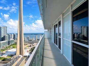 Un balcón con vista a la ciudad, ventanas amplias y cielo despejado.