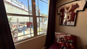 Una habitación con un ventanal grande, una silla roja y una camiseta colgada en la pared.