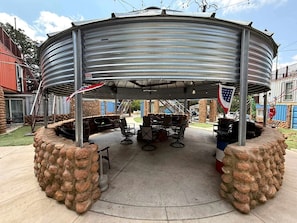 A covered outdoor seating area with stone walls, metal roof, and American flags.