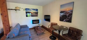 A living room with a sofa, a coffee table, a fireplace, a TV, and a painting.