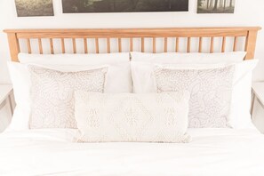 A bed with a wooden headboard, white bedding, and patterned pillows. - Cosy 2 Bedroom Cottage in Ballater (Aberdeenshire)