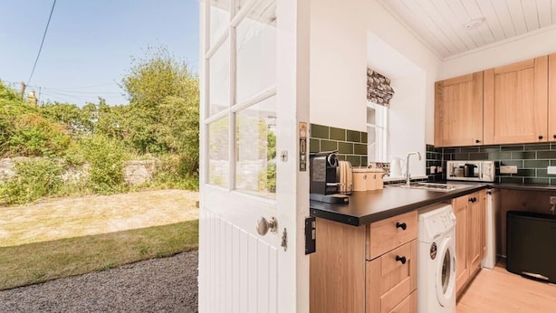 Una cocina con armarios de madera, lavadora integrada y vistas al exterior.