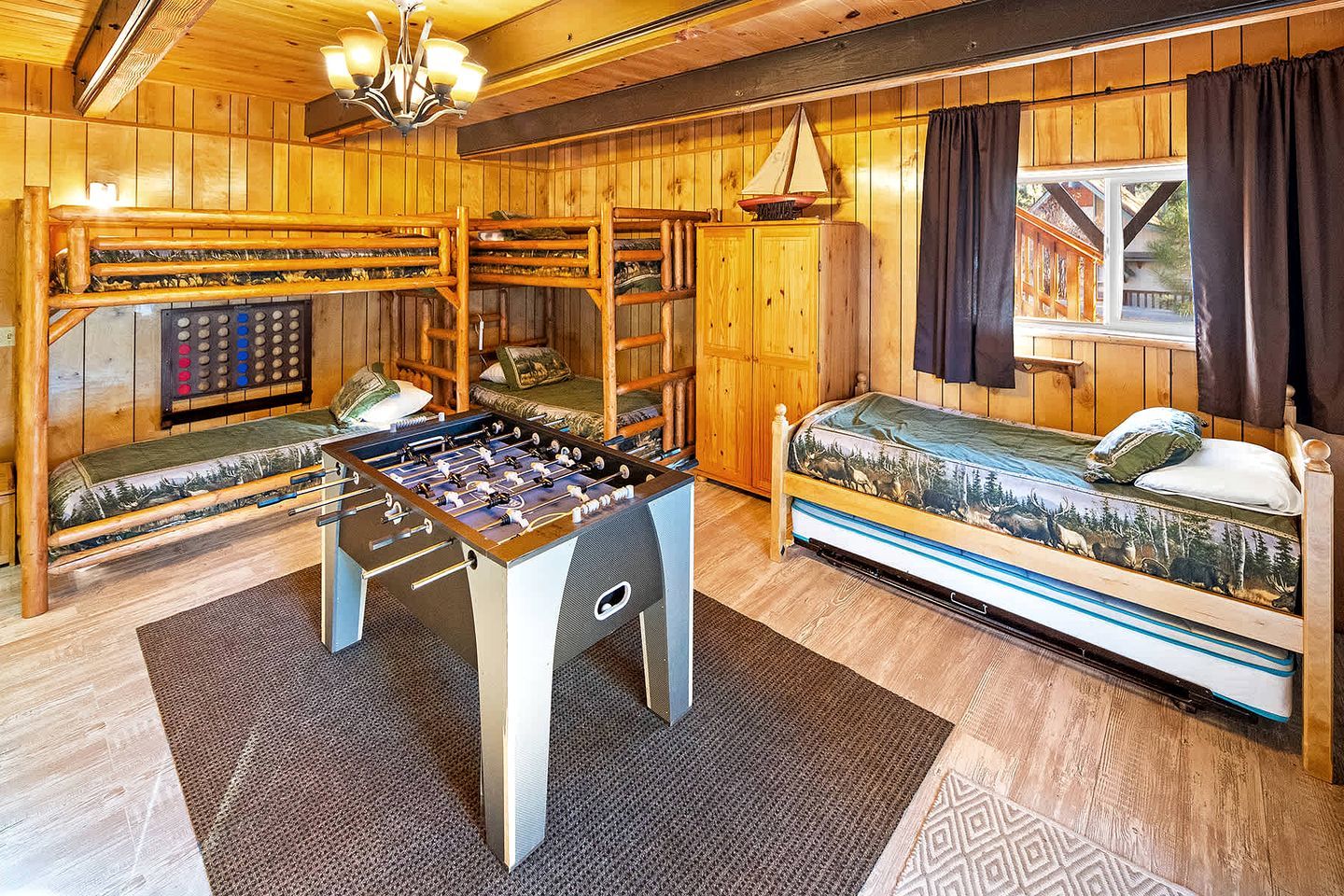 A cozy room with a foosball table, a bed with a forest-themed mattress, and a wooden cabinet with a control panel.