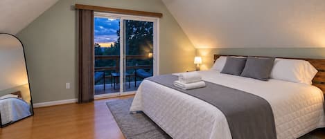 A bedroom with a bed, a ceiling fan, a nightstand, a lamp, and a view of the outdoors through a sliding door.