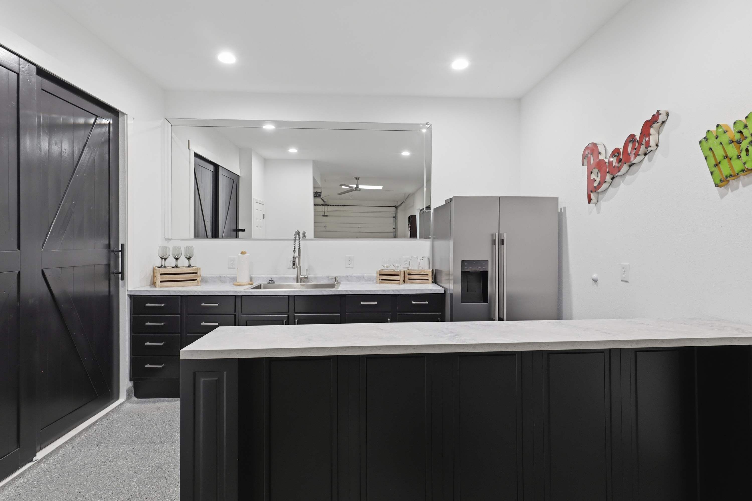 Une cuisine moderne avec des meubles de couleur sombre, un grand îlot central et un réfrigérateur.