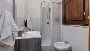 Et badeværelse med bruser, håndvask og toilet.
