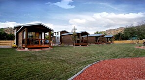Un quartier résidentiel composé de plusieurs maisons en bois, avec une pelouse bien entretenue et un paysage vallonné en arrière-plan.