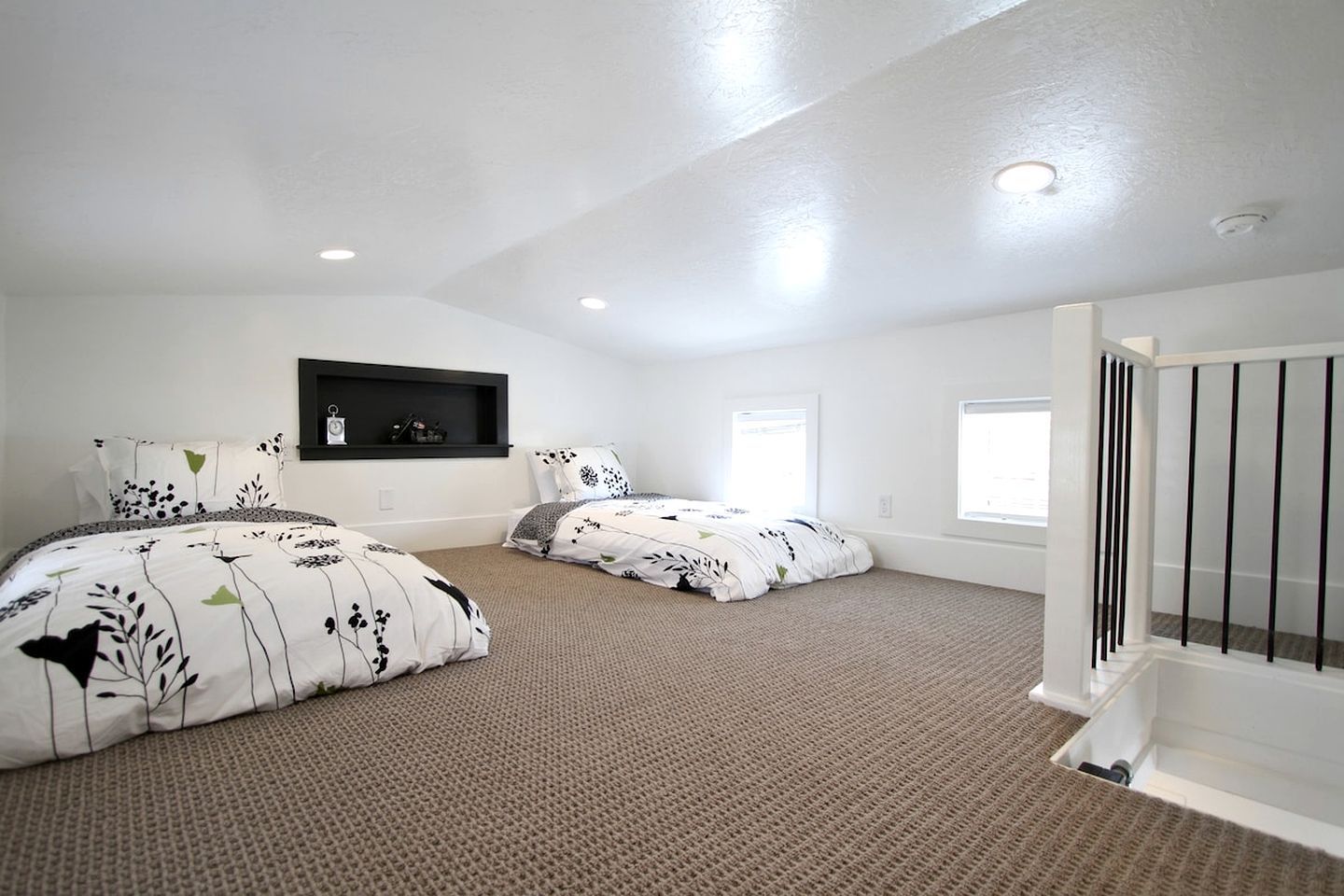 A bedroom with two beds, a built-in shelf, and a window.