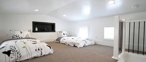 A bedroom with two beds, a built-in shelf, and a window.