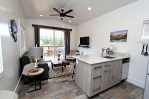 A modern kitchen with a central island, a dining area with a sofa and table, and a balcony with outdoor furniture. - Unique Escape for Four near the Zion National Park, Utah (Orderville)