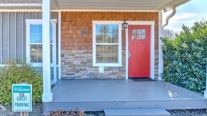 A building with a red door, a welcome sign, and a guest parking sign. - The Fairview Hideaway (Fairview)